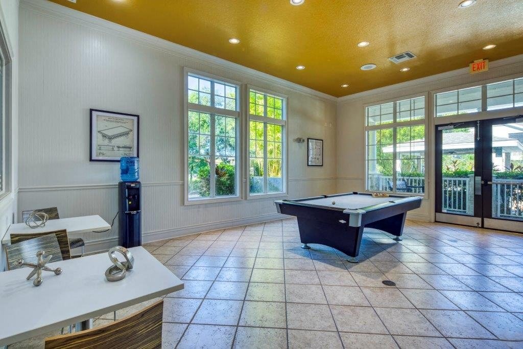 A pool table is in the middle of a room with a white table and chairs. A pool table is in the middle of a room with a white table and chairs at Rivertree Apartments, Riverview, Florida