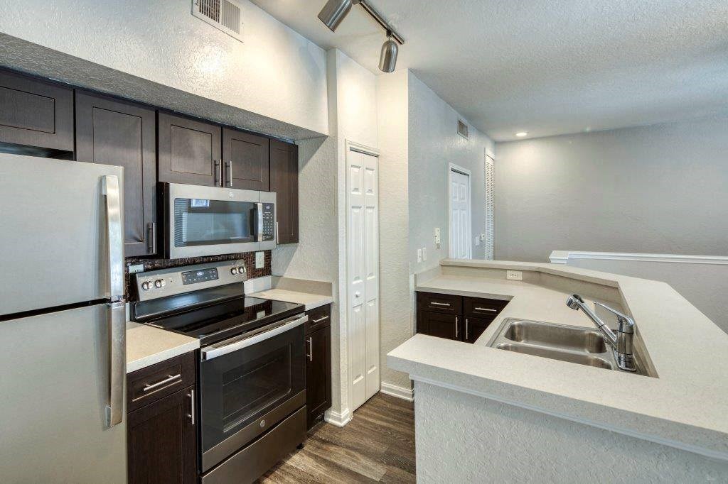 A kitchen with a white refrigerator, black cabinets, and a white countertop. A kitchen with a white refrigerator, black cabinets, and a white countertop at Rivertree Apartments, Riverview, FL