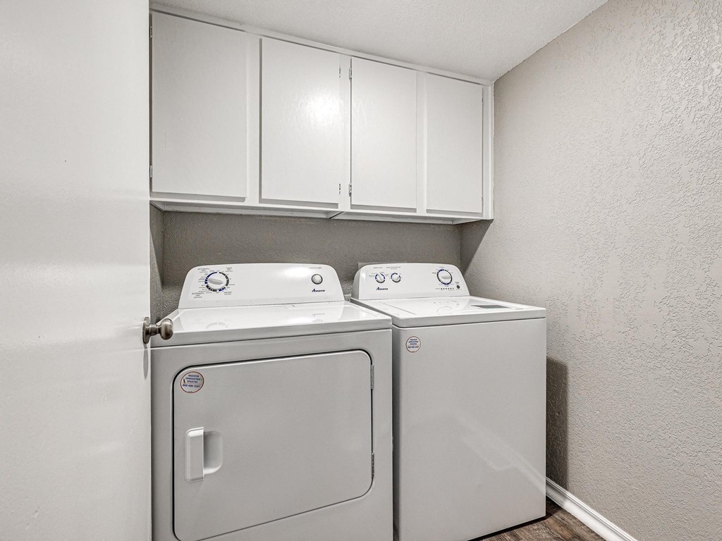 a washer and dryer in an empty laundry room with white cabinets