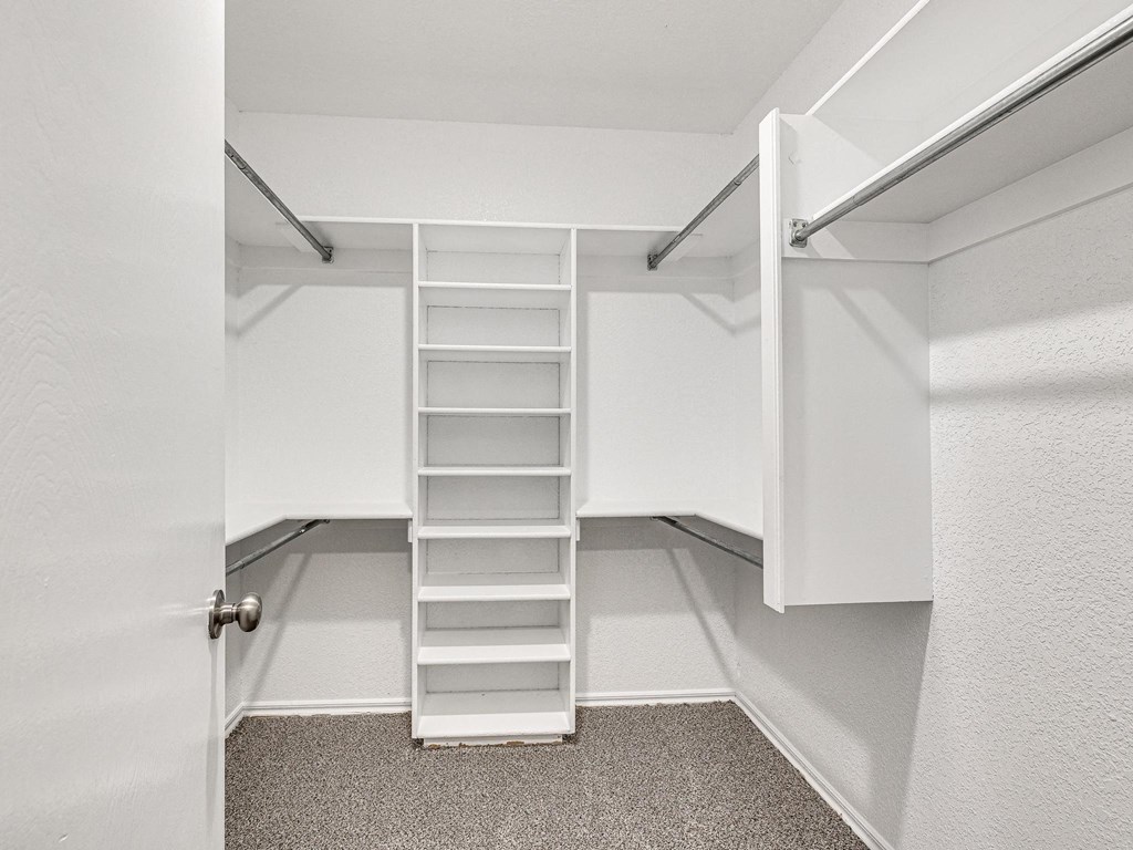 a walk in closet with white shelves and a ladder