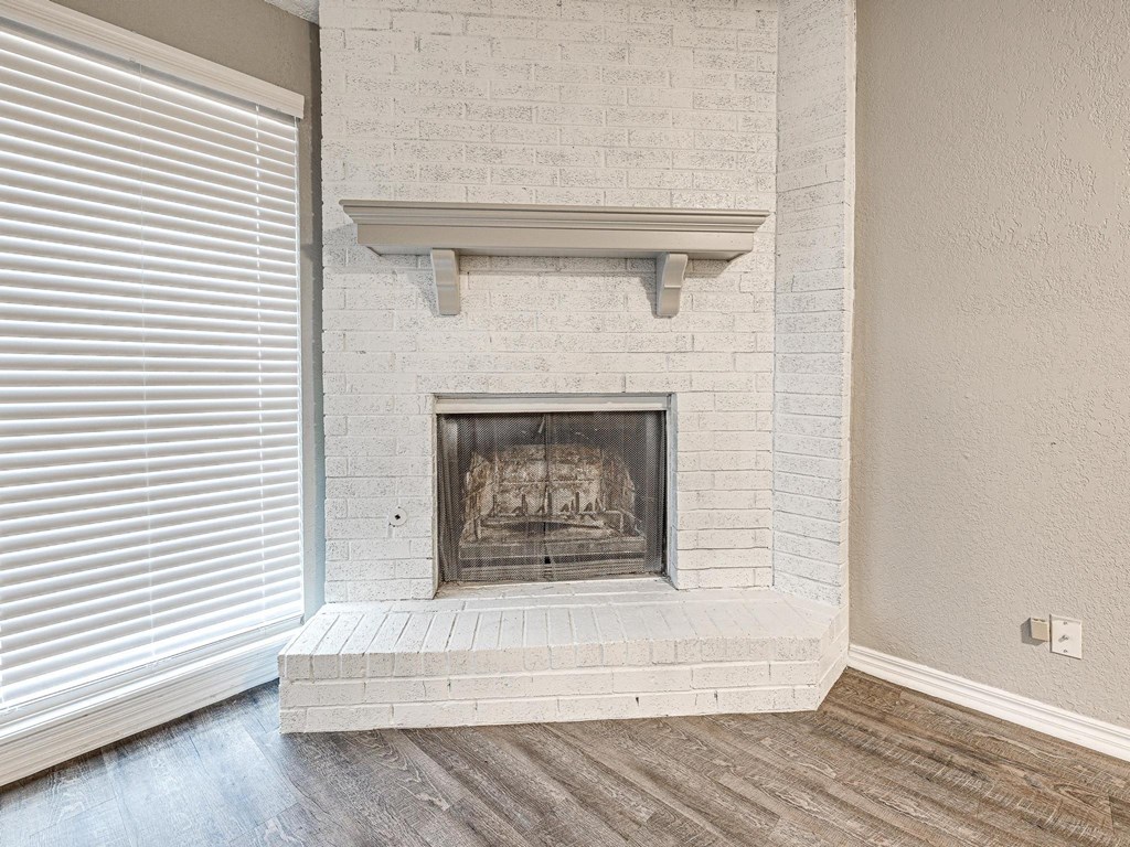 a white brick fireplace in a living room with a window