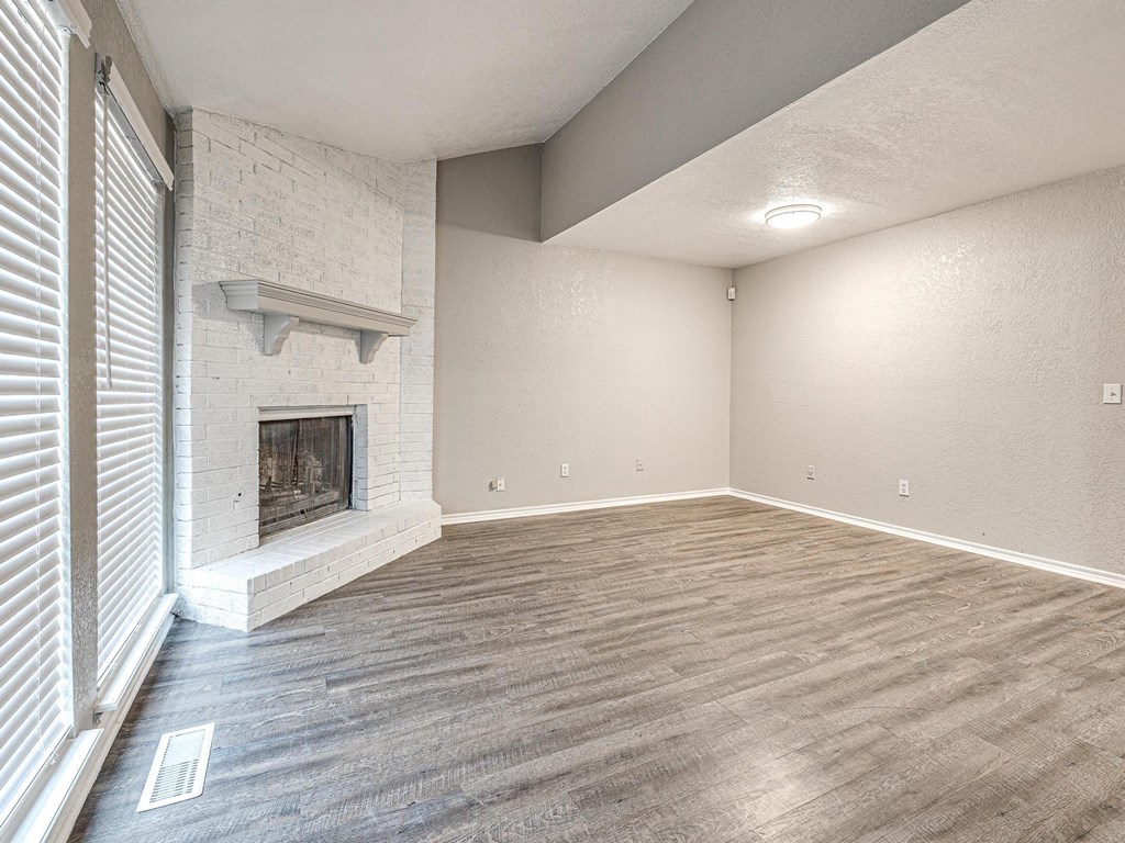 an empty living room with a fireplace and wood flooring