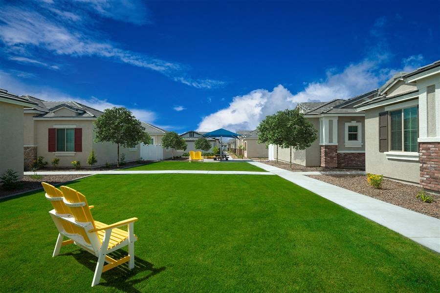 a lawn with two chairs in a yard in front of houses