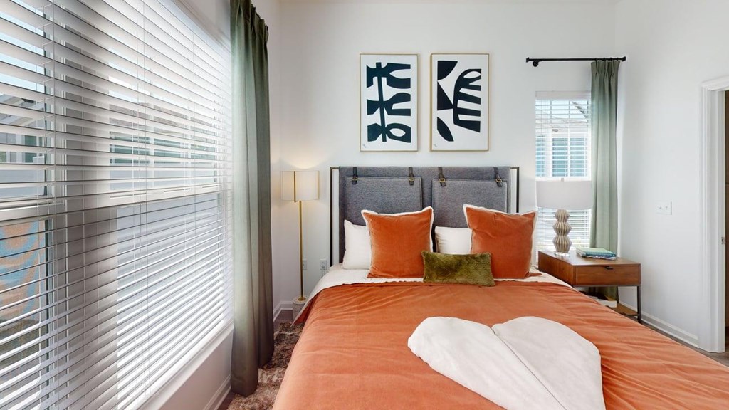 A bedroom with a bed, pillows, and two framed artworks on the wall.