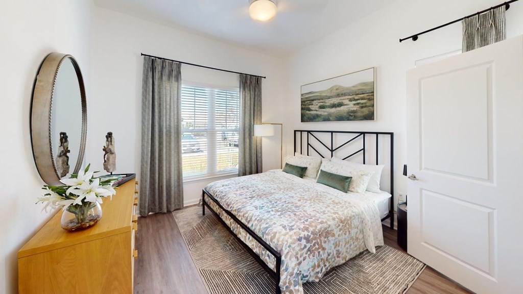 A bedroom with a bed, dresser, and mirror.