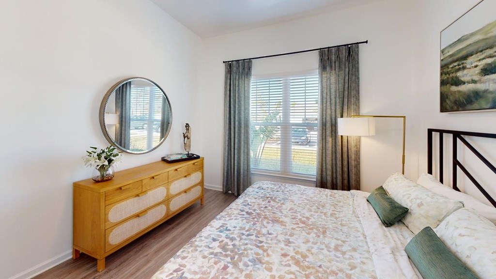 A bedroom with a bed, dresser, and window with curtains.