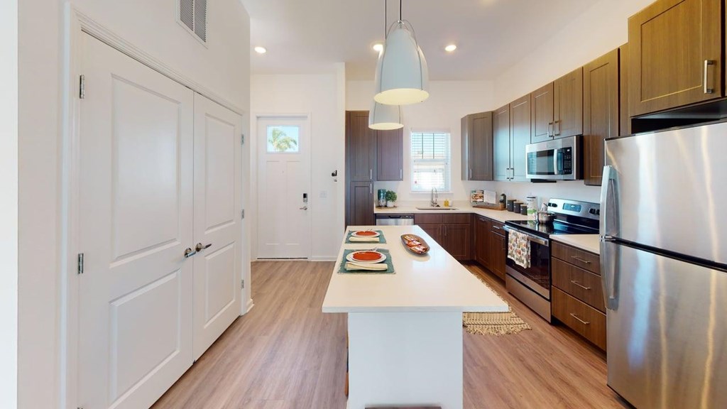 A kitchen with a white island in the middle and a refrigerator on the right.