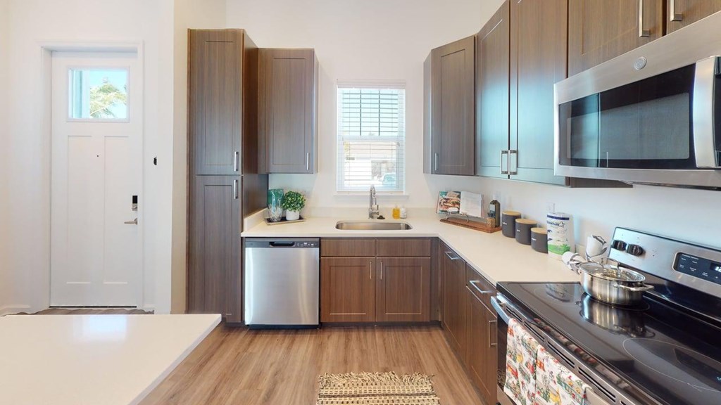 A modern kitchen with dark wood cabinets and stainless steel appliances.