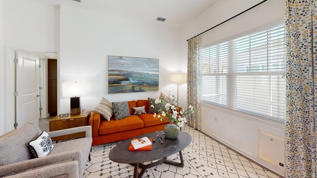A living room with a grey couch, a coffee table, and a painting on the wall.