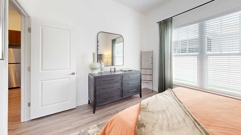 A bedroom with a bed, dresser, and mirror.
