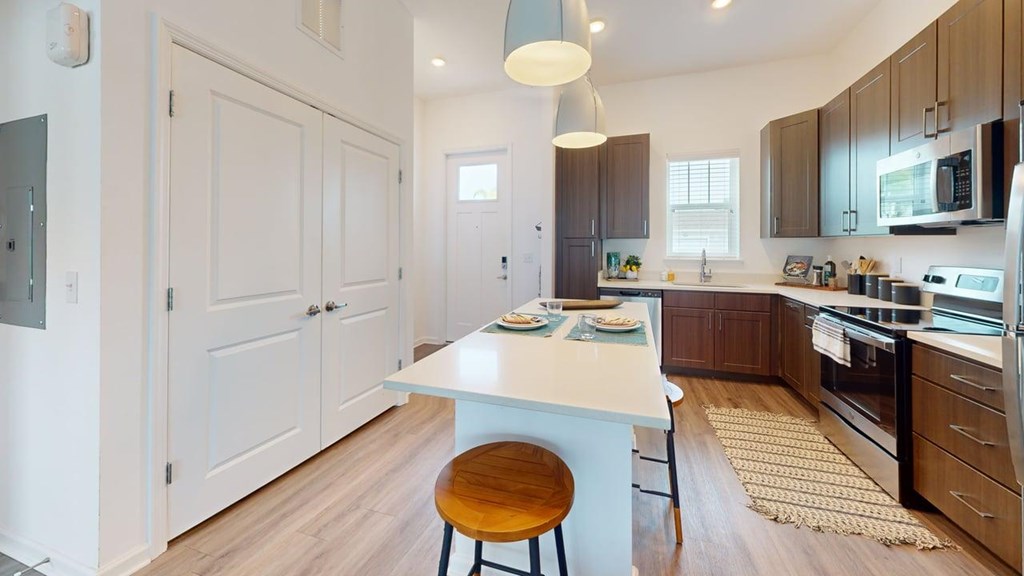 A kitchen with a white island and wooden floors.
