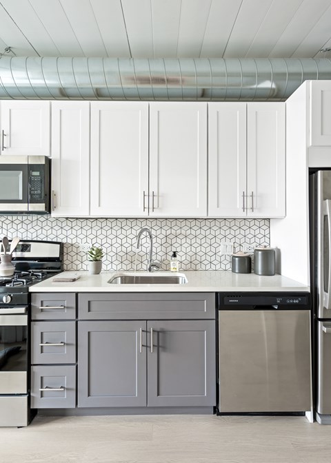 A modern kitchen with white cabinets and a black microwave.