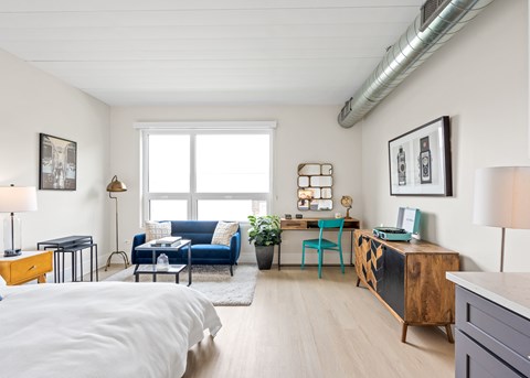 A living room with a blue couch and a white bedspread.