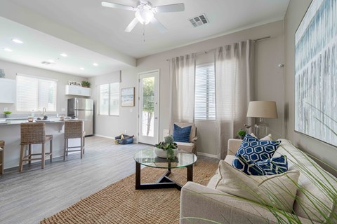 A well-lit living room with a couch, chairs, and a dining table. at Vistoria At Country Place Apartments, Tolleson, Arizona