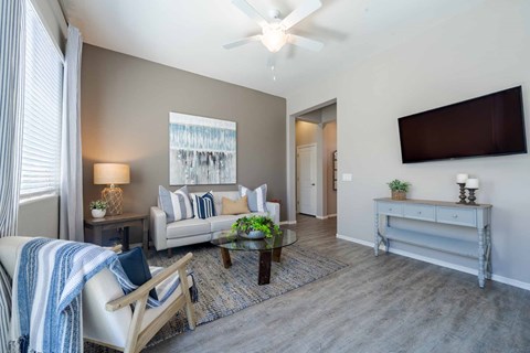 A living room with a couch, a chair, a coffee table, and a flat-screen TV mounted on the wall.