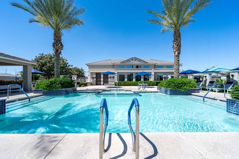 A swimming pool surrounded by palm trees and a building in the background at Vistoria At Marley Park Apartments, Arizona, 85379