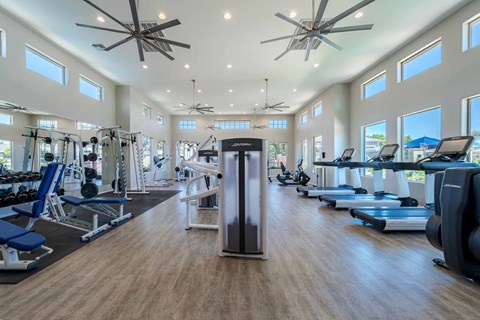 A spacious gym with a variety of equipment and a ceiling fan at Vistoria At Marley Park Apartments, Surprise, 85379