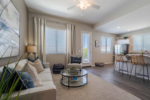 A living room with a white couch, a glass coffee table, and a painting on the wall.