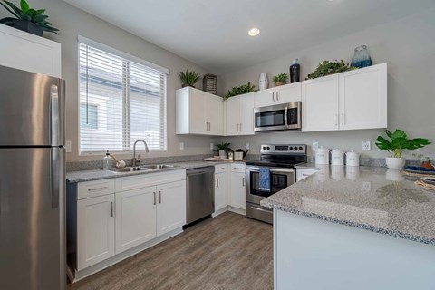A kitchen with white cabinets and a granite countertop.