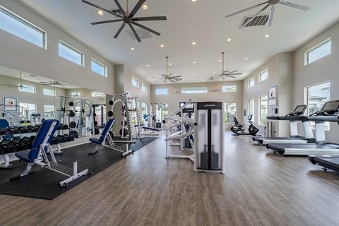 A spacious gym with a variety of equipment and a ceiling fan.