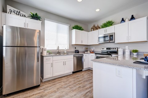 A kitchen with white cabinets and a stainless steel refrigerator.