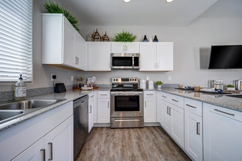 A kitchen with white cabinets and a wooden floor.