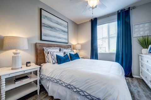 A bedroom with a large bed and a painting on the wall.