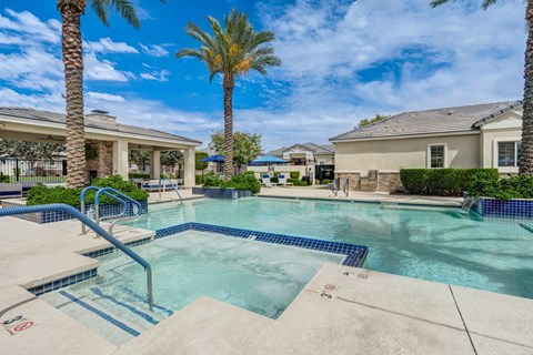 A swimming pool surrounded by palm trees and residential buildings.
