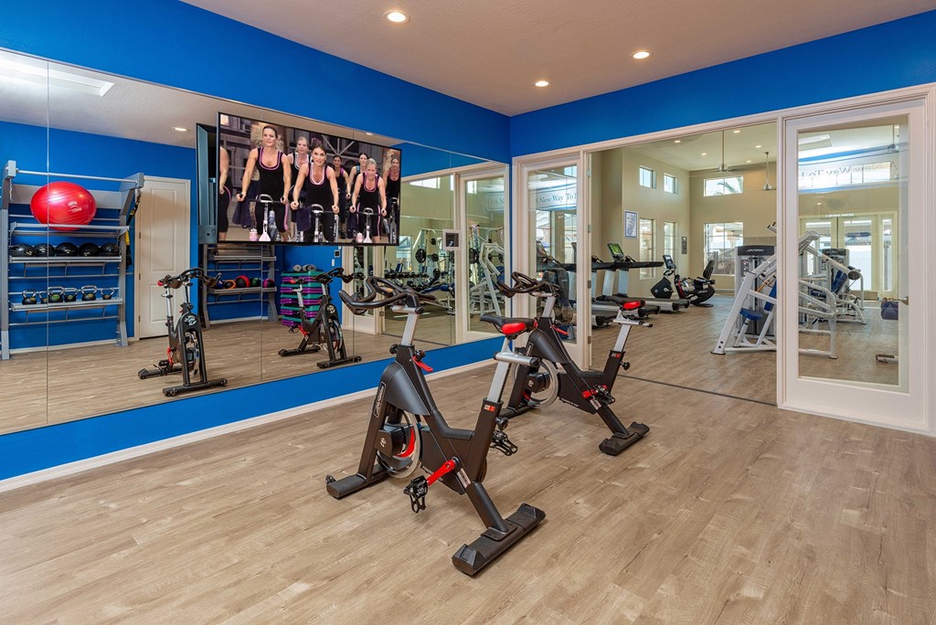 a gym with exercise equipment and a large screen on the wall