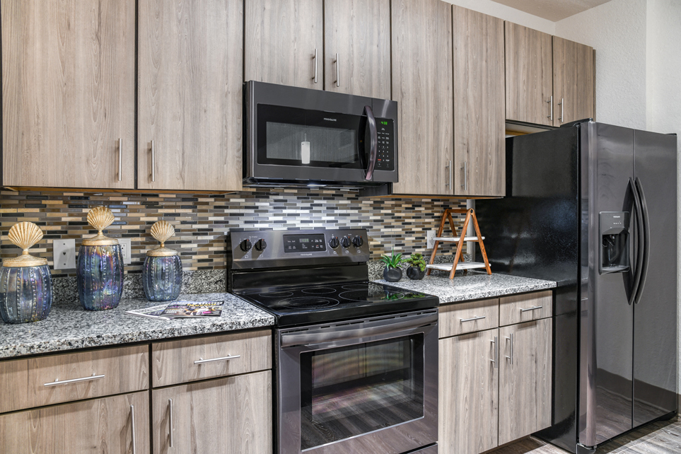A kitchen with wooden cabinets and a black refrigerator.