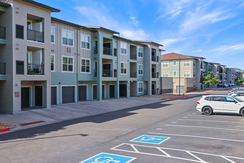A white car is parked in a parking lot with a blue and white handicap sign.