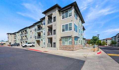 A modern apartment building with a parking lot in front.