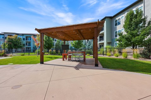 A wooden pavilion with a bench is in the middle of a paved area.