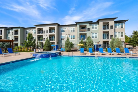 A large swimming pool in front of apartment buildings.