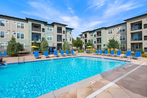 A large swimming pool in front of apartment buildings.
