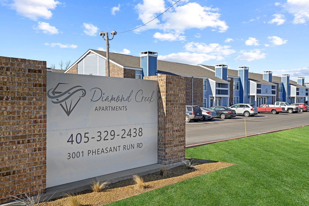 white sign that says Diamond Creek with brick surrounding it