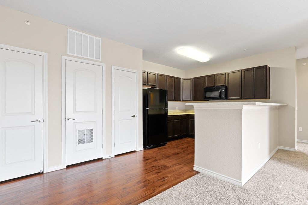 a kitchen with dark cabinets and a white island with a black refrigerator
