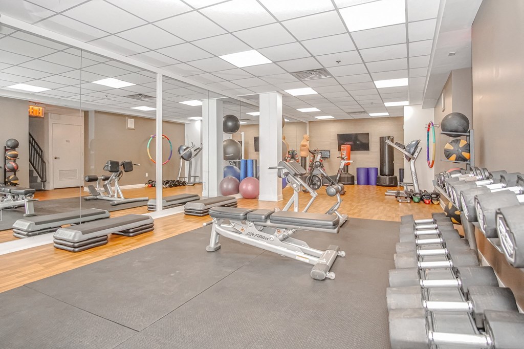 a gym with cardio equipment and weights on the floor at 10 West Apartments, Long Beach, 11561