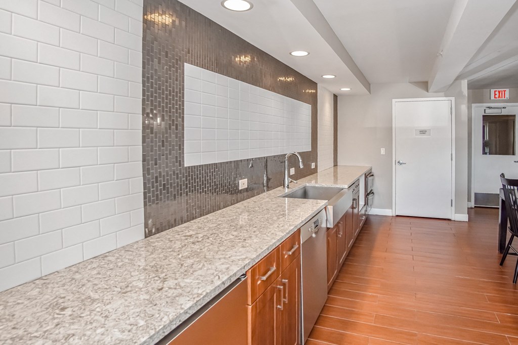 a long kitchen with granite counter tops and a sink at 10 West Apartments, New York