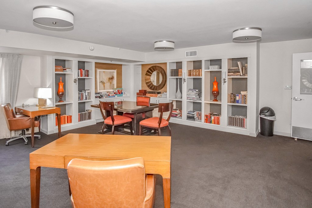 a club house with tables and chairs and bookshelves at 10 West Apartments, Long Beach, 11561