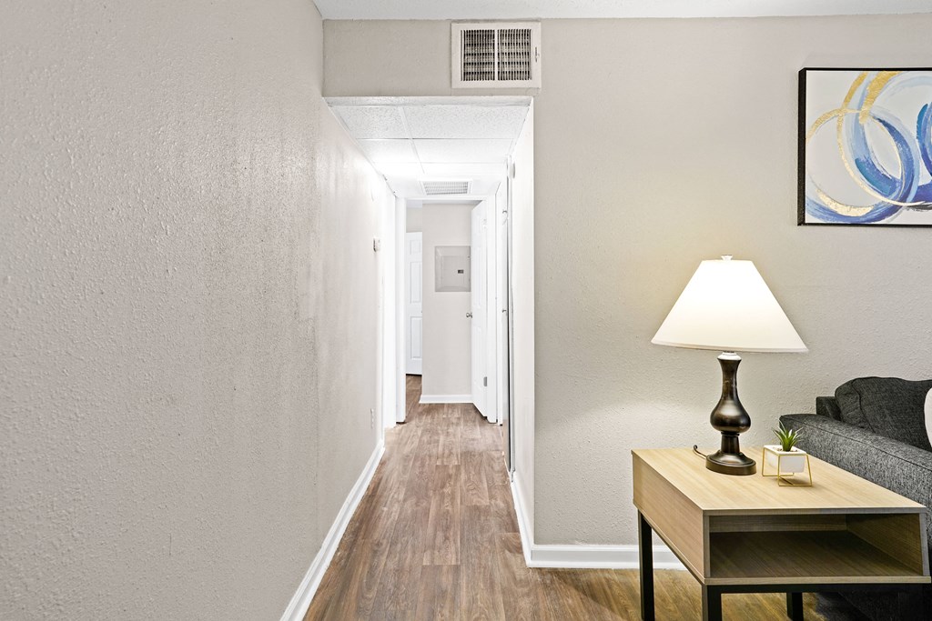 a living room with a lamp and a couch and a hallway with a door to at Diamond  Trail Apartments, Oklahoma City, 73112