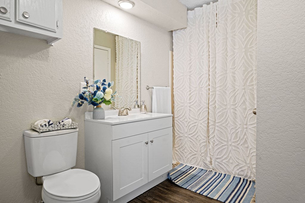 bathroom with white toilet and white cabinet with blue flowers on top