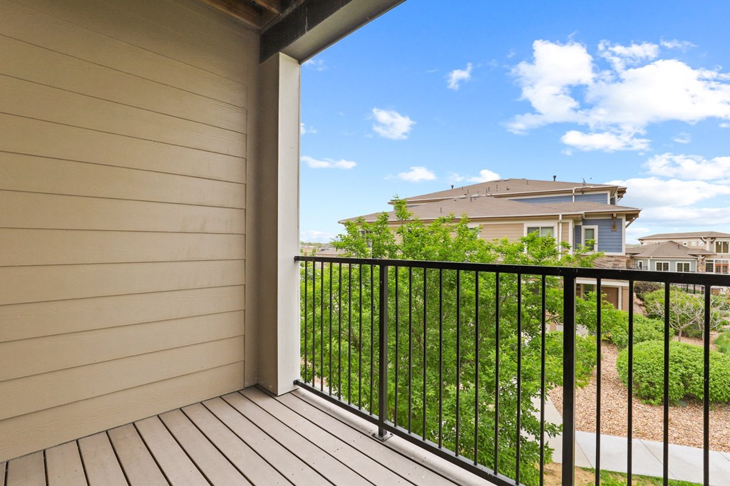 a balcony with a view of the yard and houses in the background