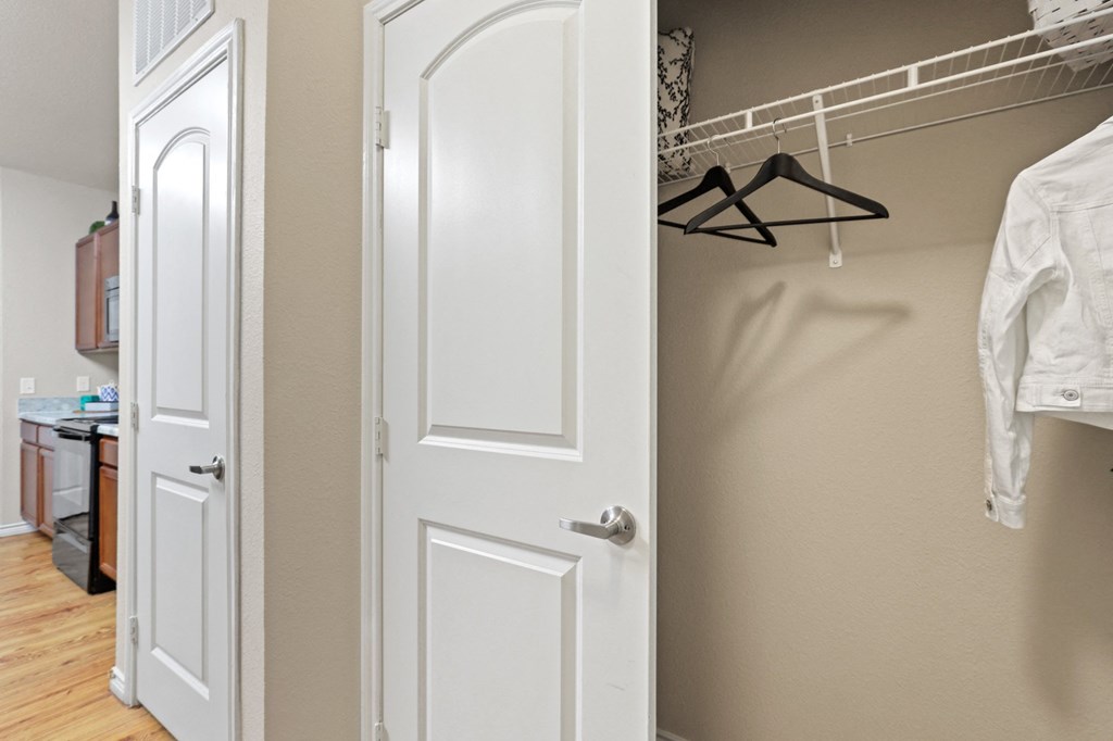 a walk in closet with a white door and a hanger on the wall