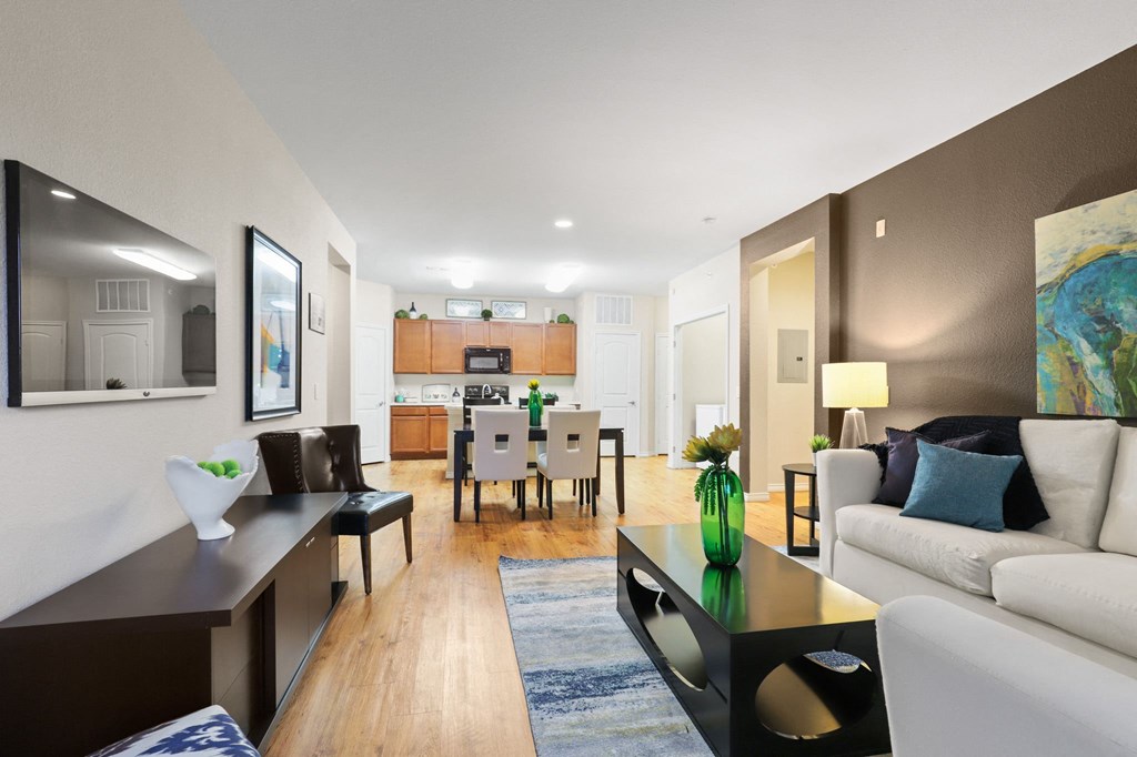 a living room with a couch coffee table and a dining room table in the background