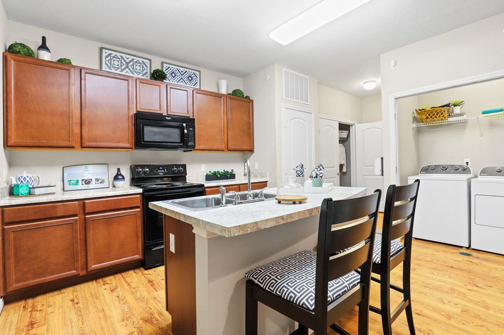 a kitchen with wooden cabinets and a white counter top with three black chairs