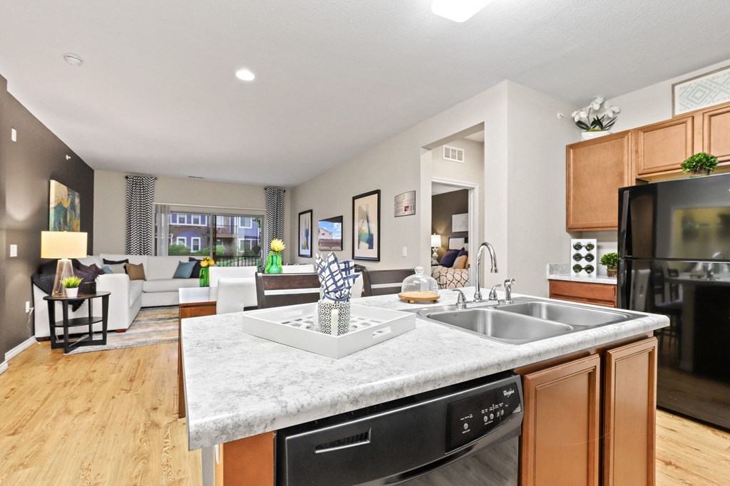 a kitchen island with a sink and a dishwasher in front of a living room with a