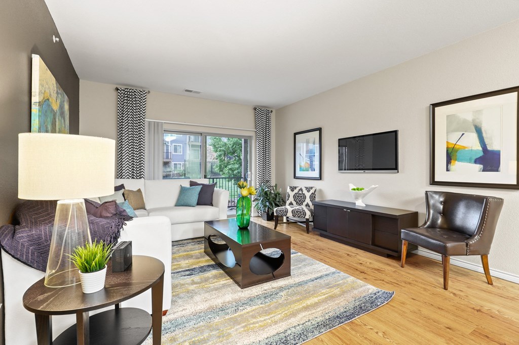 a living room with a white couch and a tv on the wall