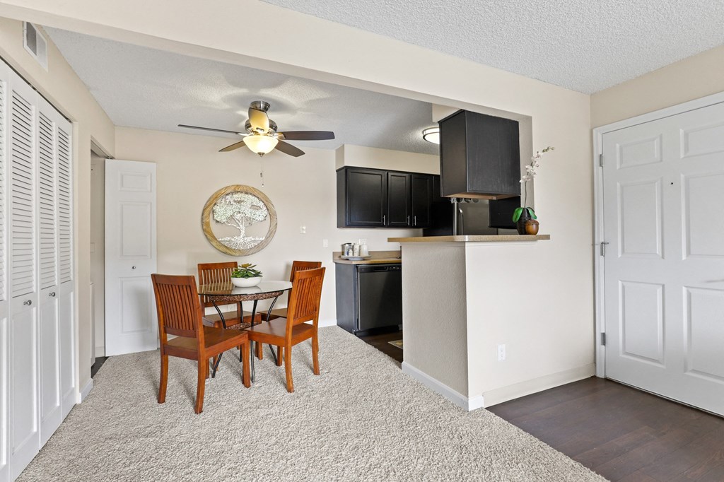 a dining area with a table and chairs and a kitchen in the background