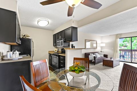 a kitchen and living room with a table and chairs and a ceiling fan